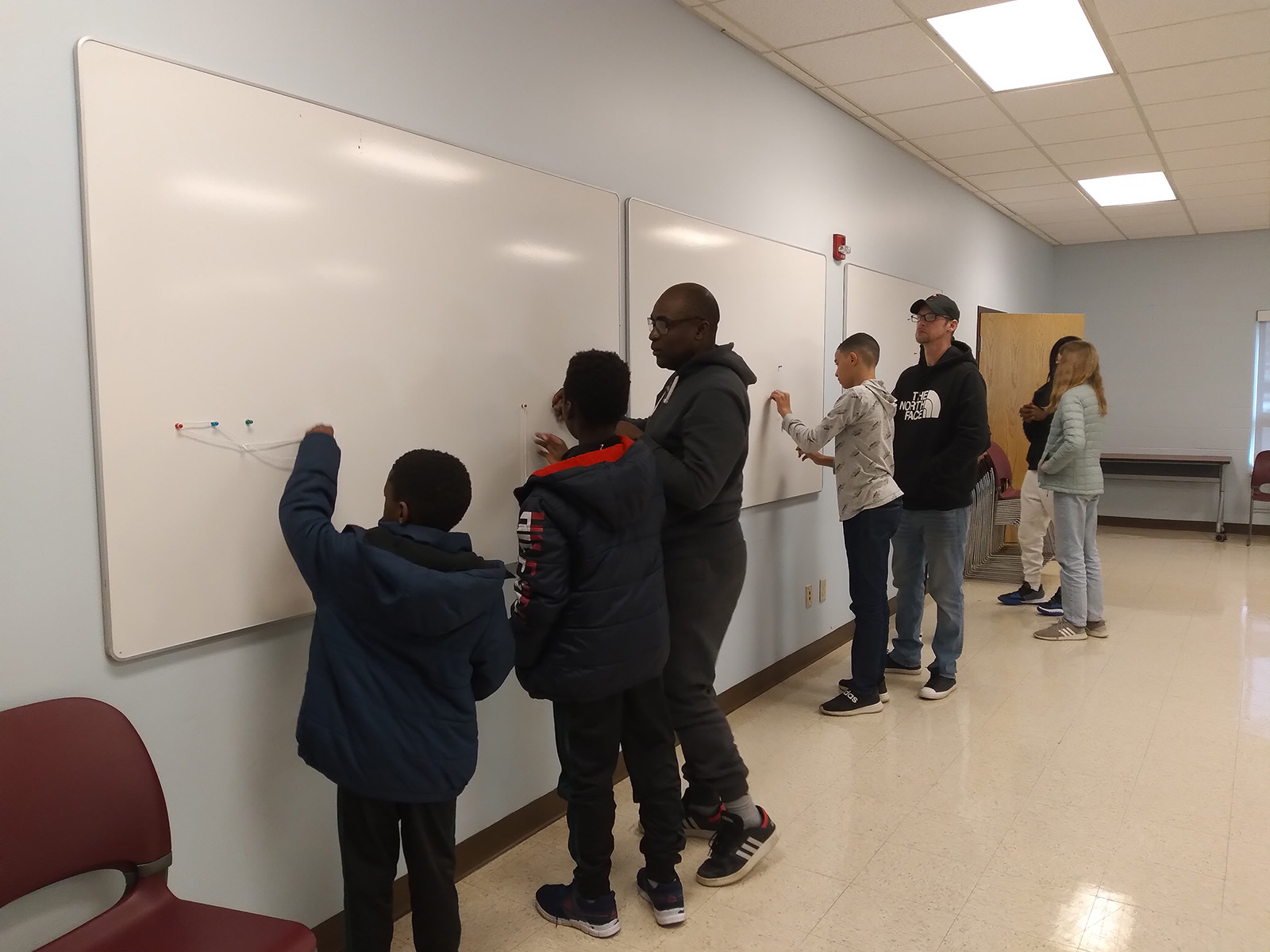 Kids and adults engaged in solving the picture hanging puzzle.