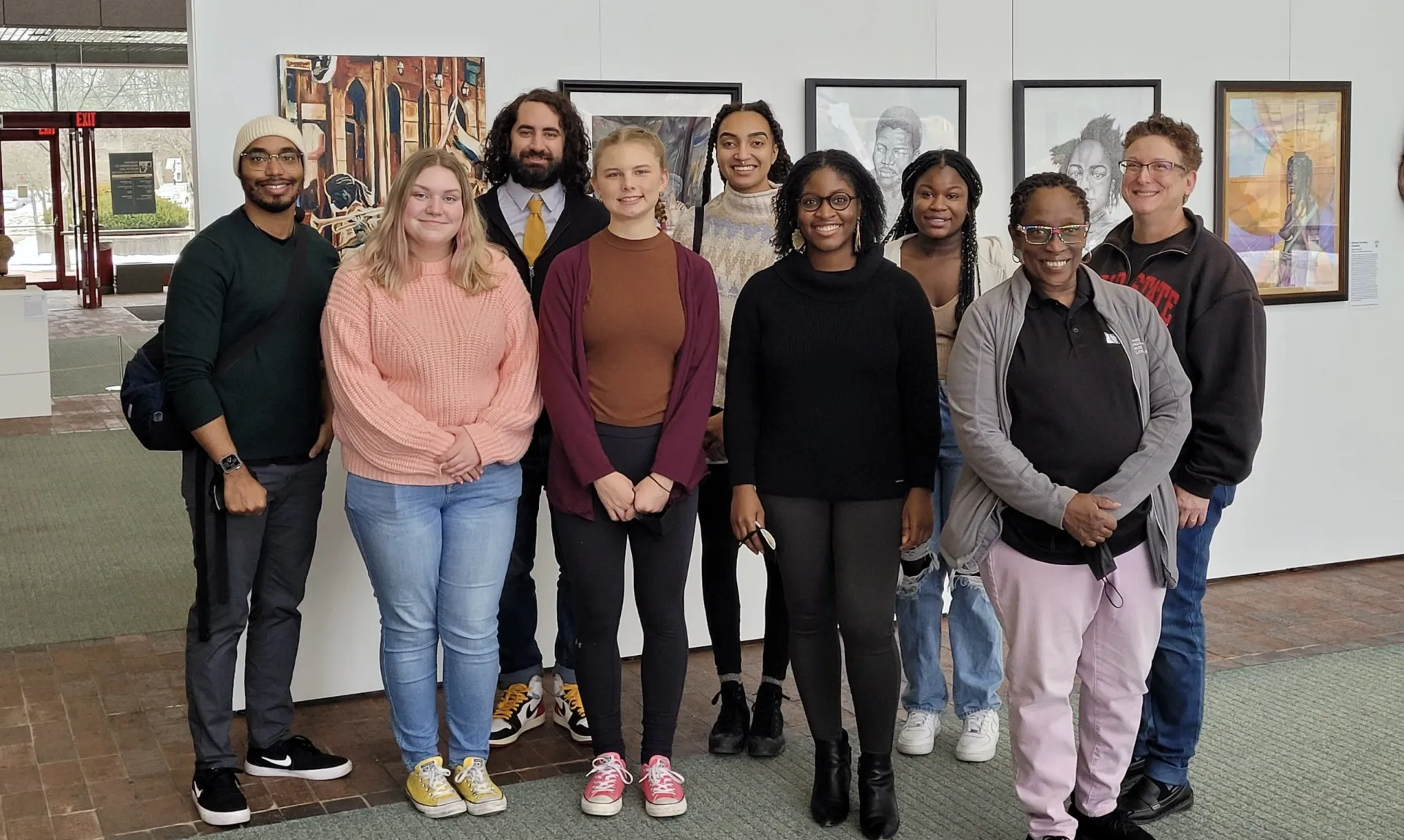 photo of team at afro American museum; 9 team member in front of hanging photos in museum gallery